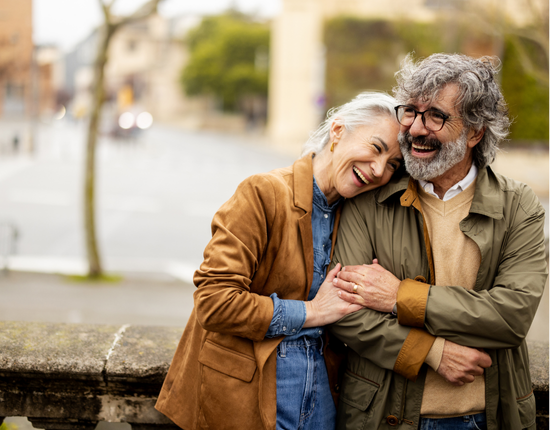 man and woman on a bridge hugging ad laughing