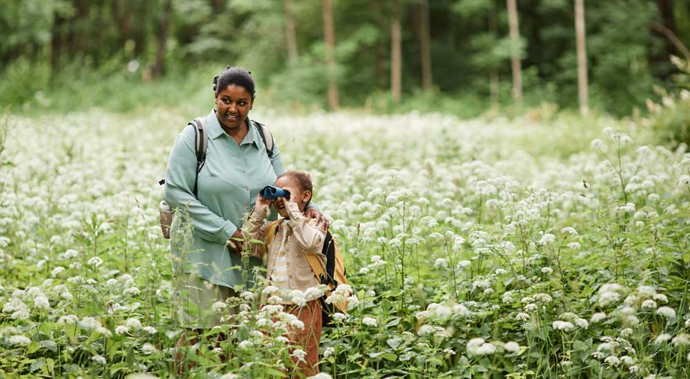 woman with little girl in meadow with binoculars